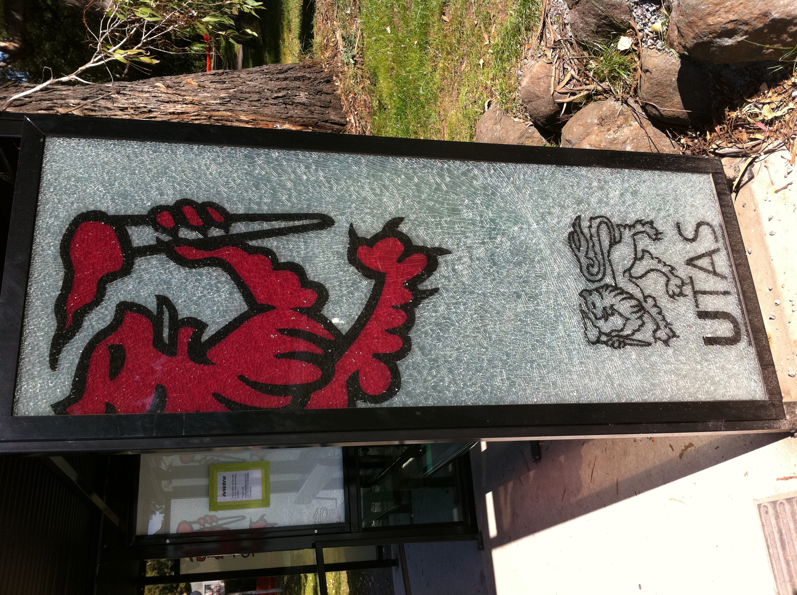 A smashed glass pane on a bus stop with the UTAS logo