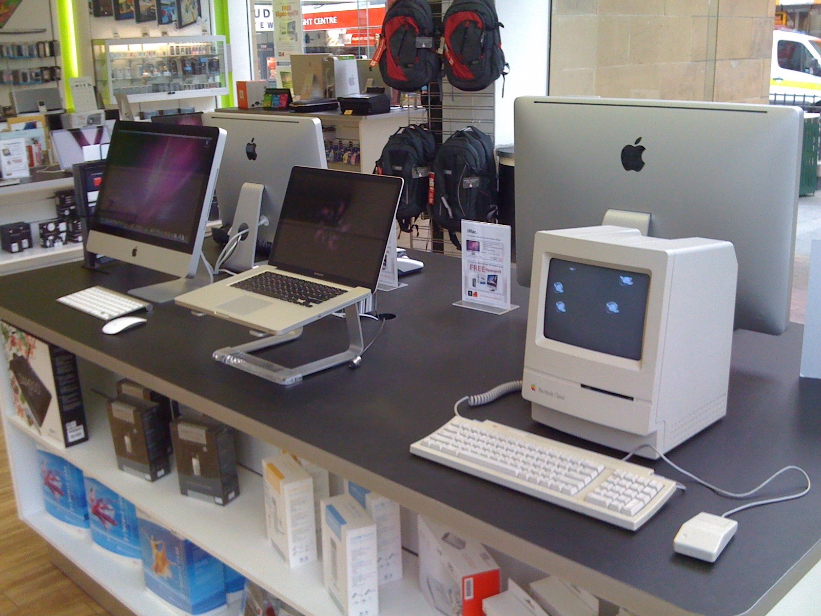 A retail display bench showcasing a Macintosh Classic next to the super-modern aluminium and glass iMac and Macbook Pro of the time