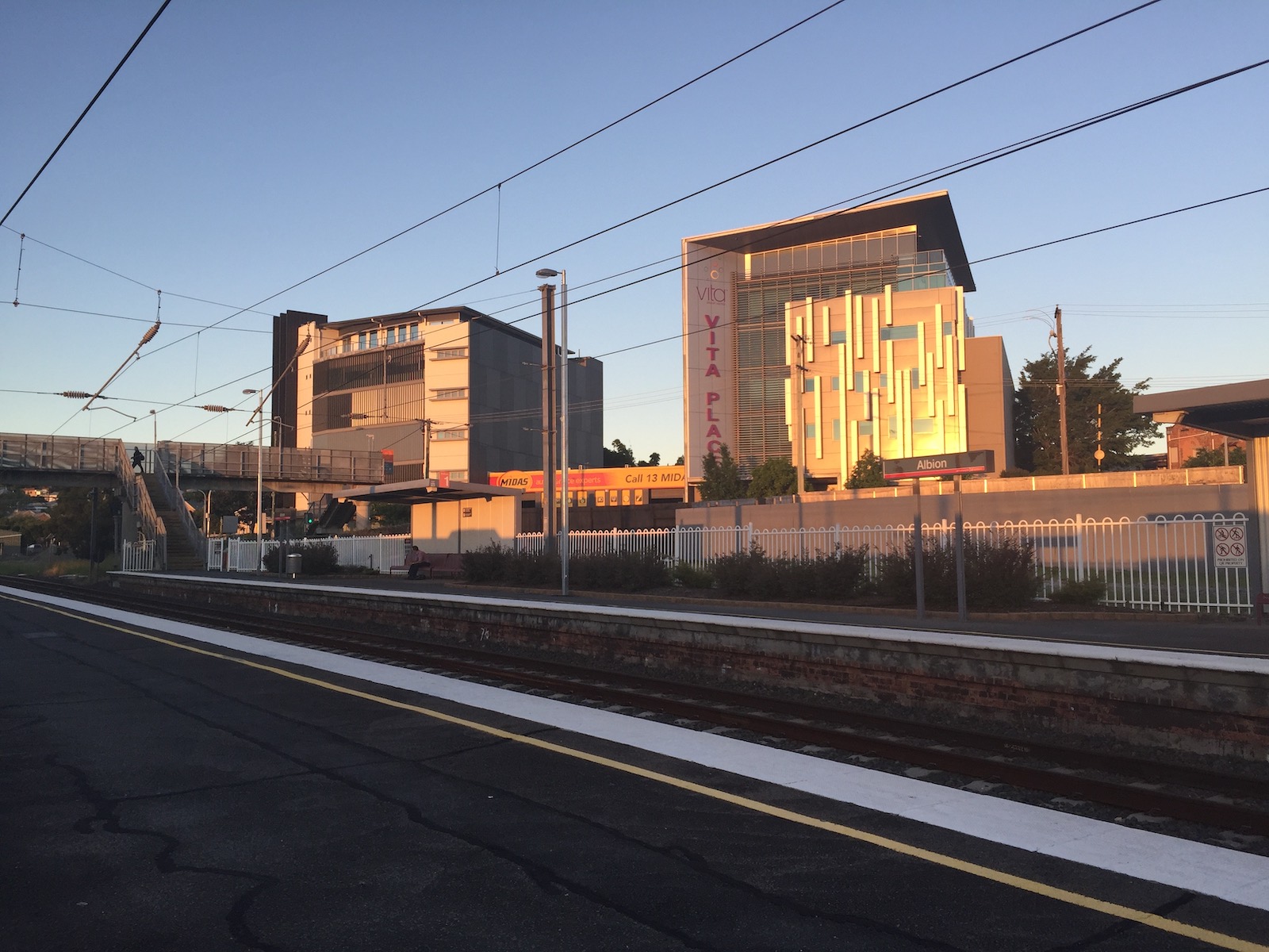 The exterior of the Vita Place building lit up by the late afternoon sunset, as seen from Albion train station