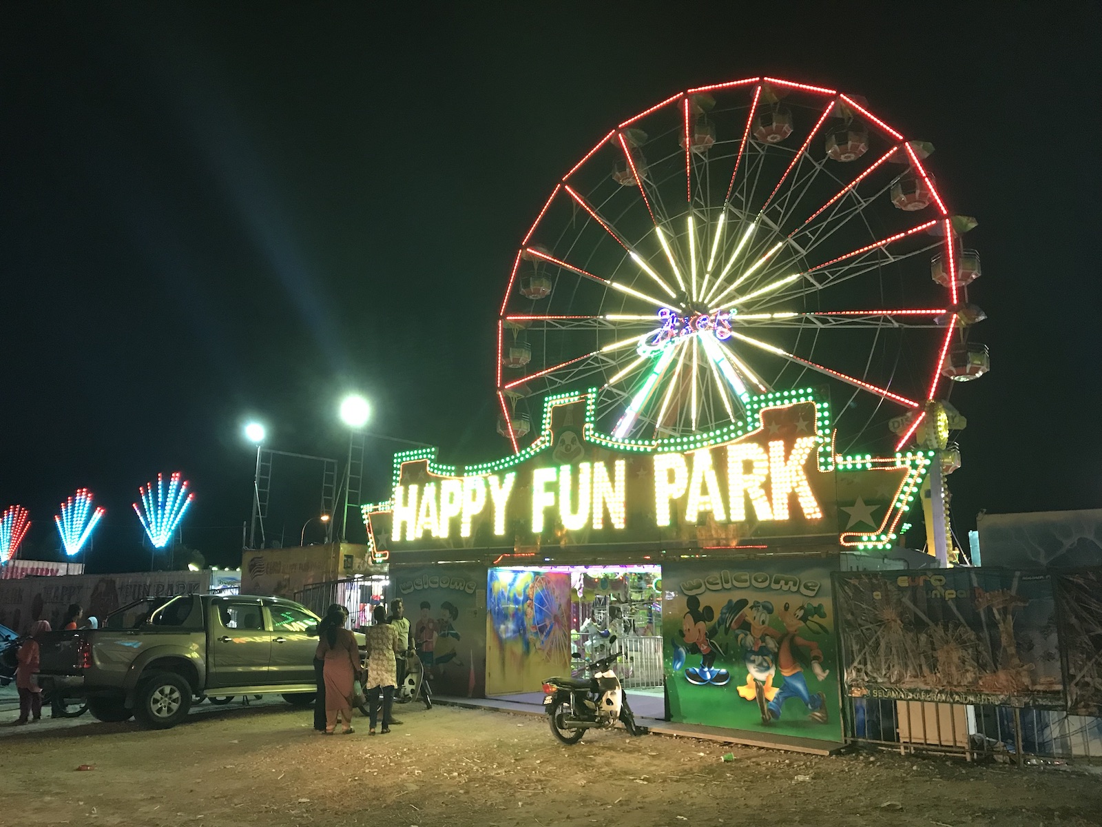 The entrance of Happy Fun Park from the carkpark, neon lights lighting up the night sky