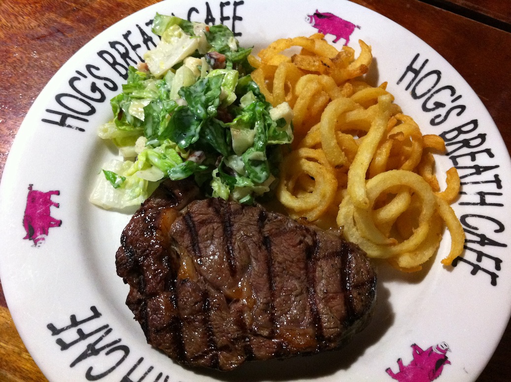Traditional steak at Hog's Breath with curly fries and caesar salad.